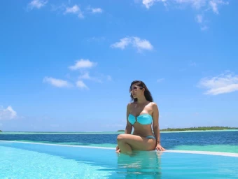 Sophie Choudry is giving pure summer vibes sitting beside a pool in a blue bikini