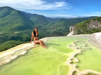 A Photo Of A Woman Wearing A Bikini, In An Aesthetic Pose, Sitting In The Hierve El Agua Oaxaca, On Top Of A Hill