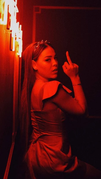 fearless photo of Danna from Elite photographed doing the middle finger gesture as she posed on the wall with red neon lights