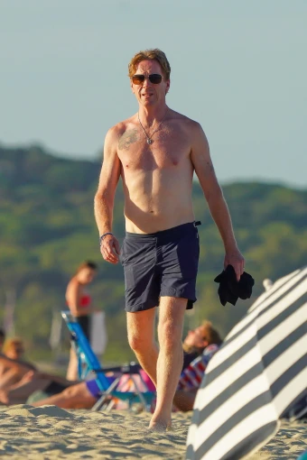 Damien Lewis goes for a shirtless stroll on the beach.