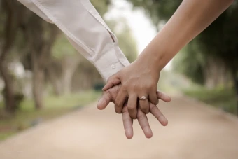 close up of an engaged couple holding hands outdoors one wears a long sleeved shirt