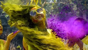 A woman smeared in coloured powder during Holi celebrations, in Nadia