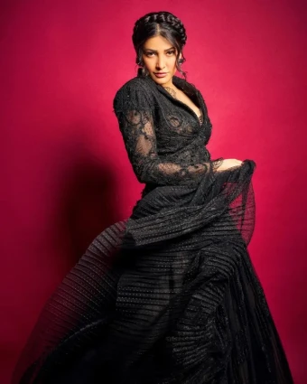 The deep red background contrasts beautifully with the black gown, enhancing the overall visual impact and making Shruti stand out