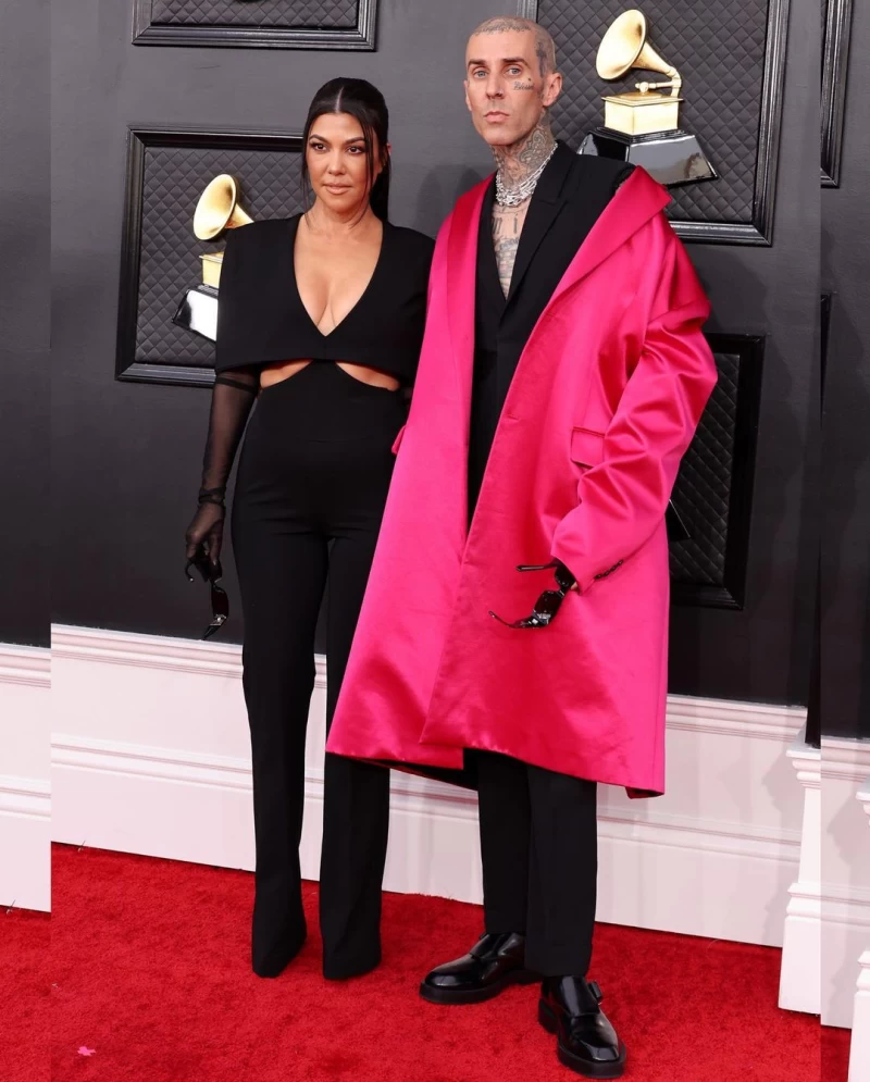 Kourtney Kardashian looked gorgeus in an EtOchs jumpsuit while Travis Barker donned a pink Raf Simmons jacket over his Givenchy suit.