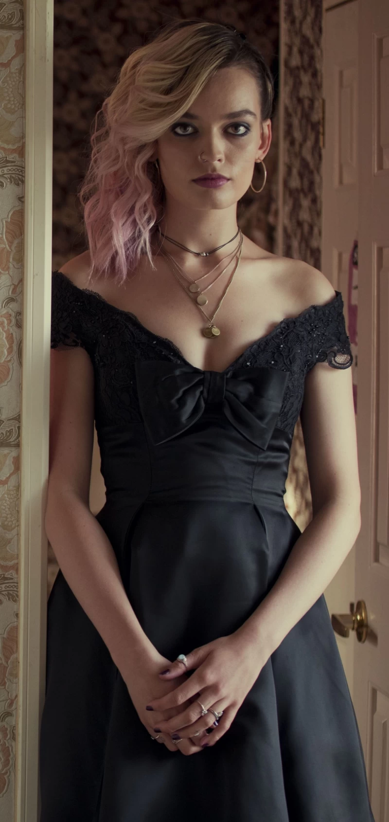 A Scene From Sex Education, The Netflix Series, Where Maeve Played By Emma Mackey, Is Wearing A Black Off-shoulder Dress.