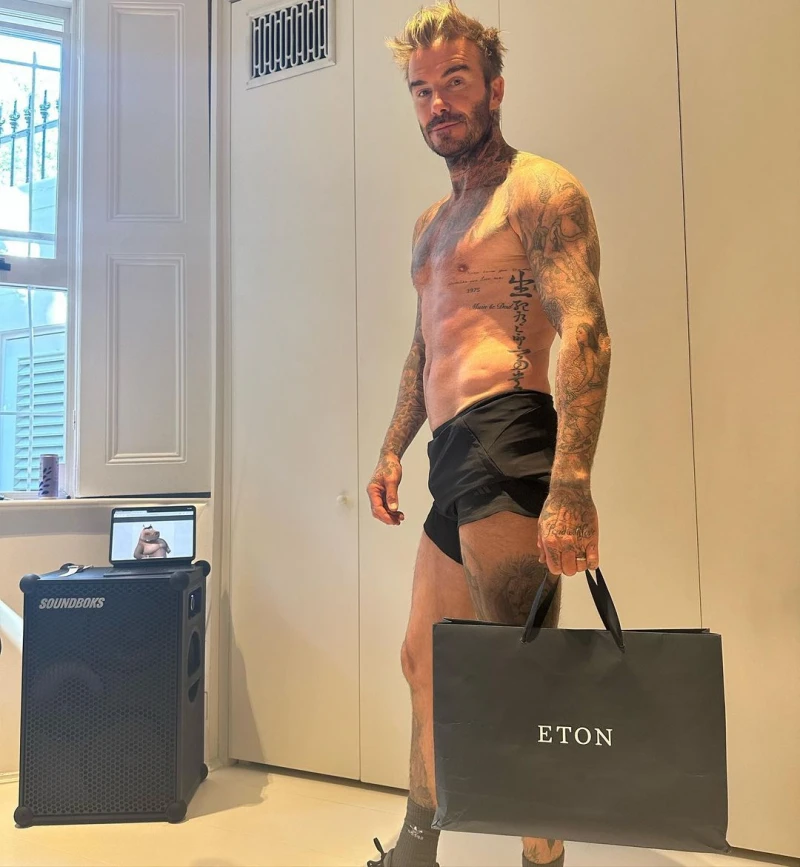 David Beckham poses shirtless with a shopping bag in his home gym