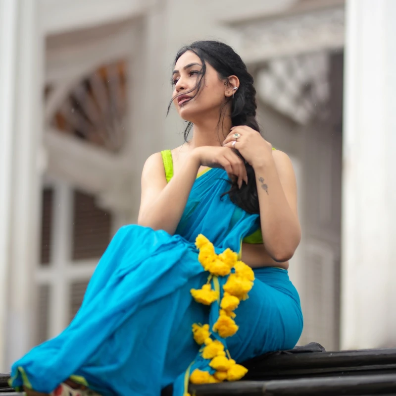 Shubhangi Atre, an Indian television actress, sits on steps wearing a blue sari, embodying grace and traditional beauty