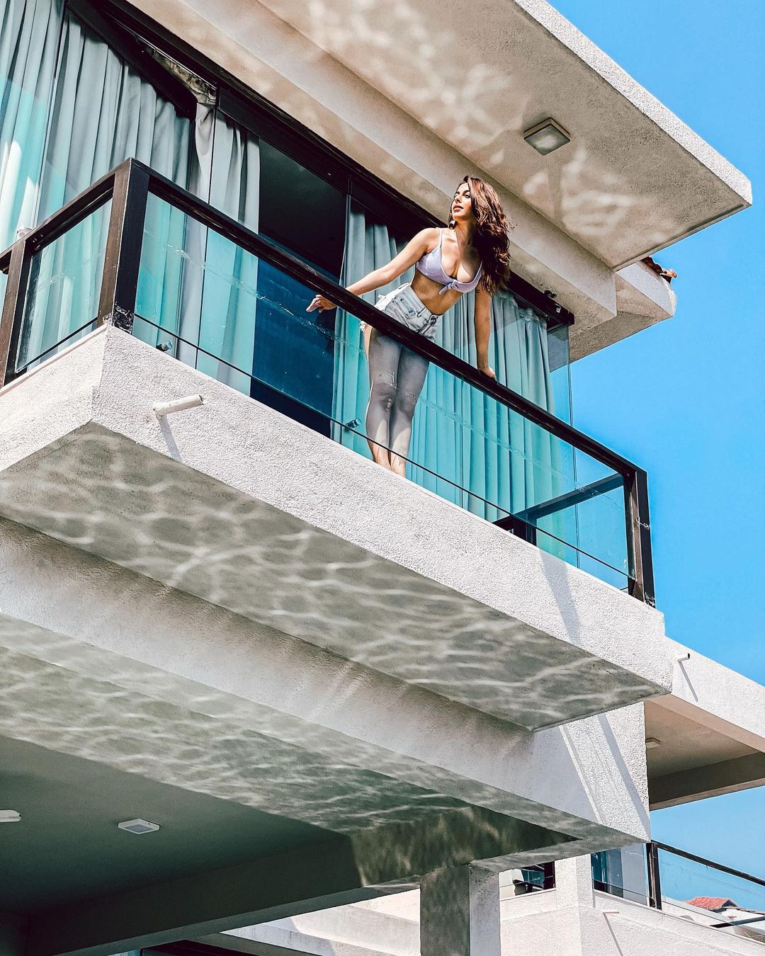 Alaya F shows off her cleavage as she leans on a balcony in a sexy blouse paired with denim shorts