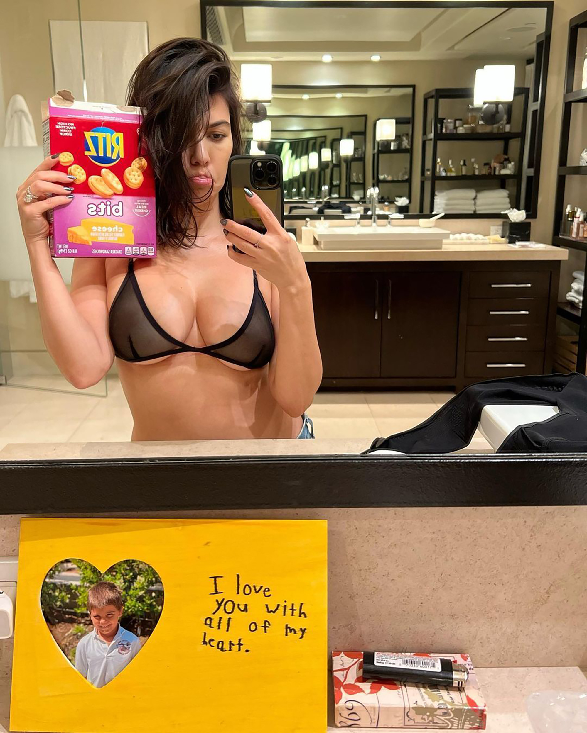 Kourtney Kardashian shares a sweet note from her son Reign while standing in her bra with a box of Ritz Bits.