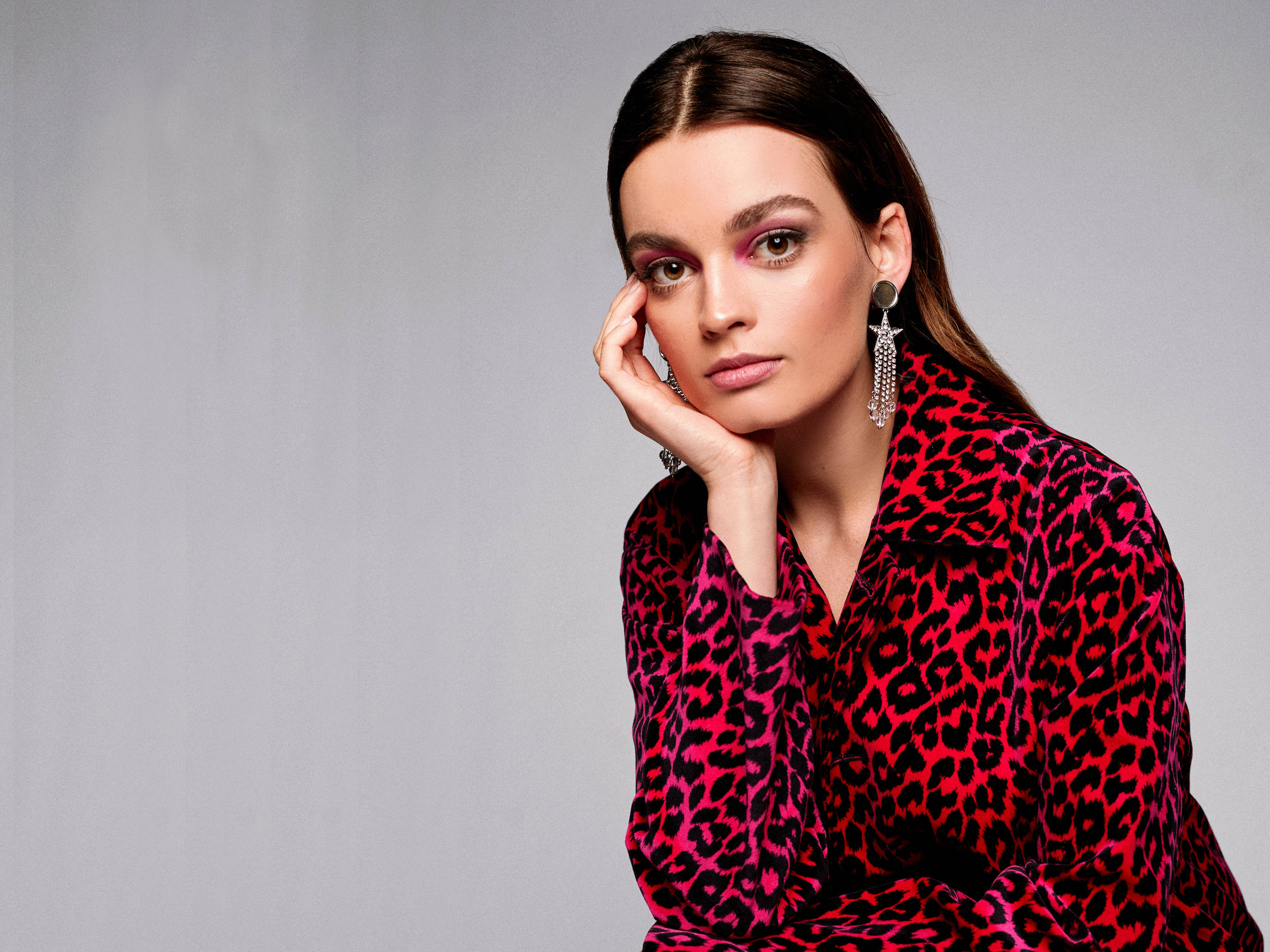 An Image Featuring Actress Emma Mackey Wearing A Trendy And Fashionable Leopard Printed Outfit Paired With Star Earrings.