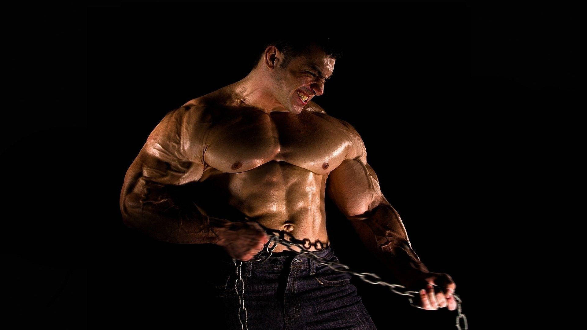 Muscular Man Pulling A Chain Against A Dark Background.