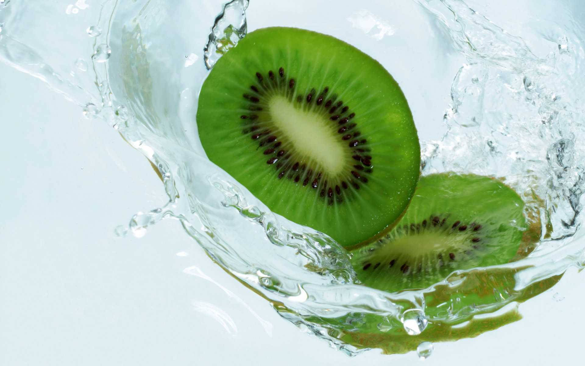 Remarkable Still Shot Of Two Kiwi Slices Showing Its Green Interiors Falling On Water