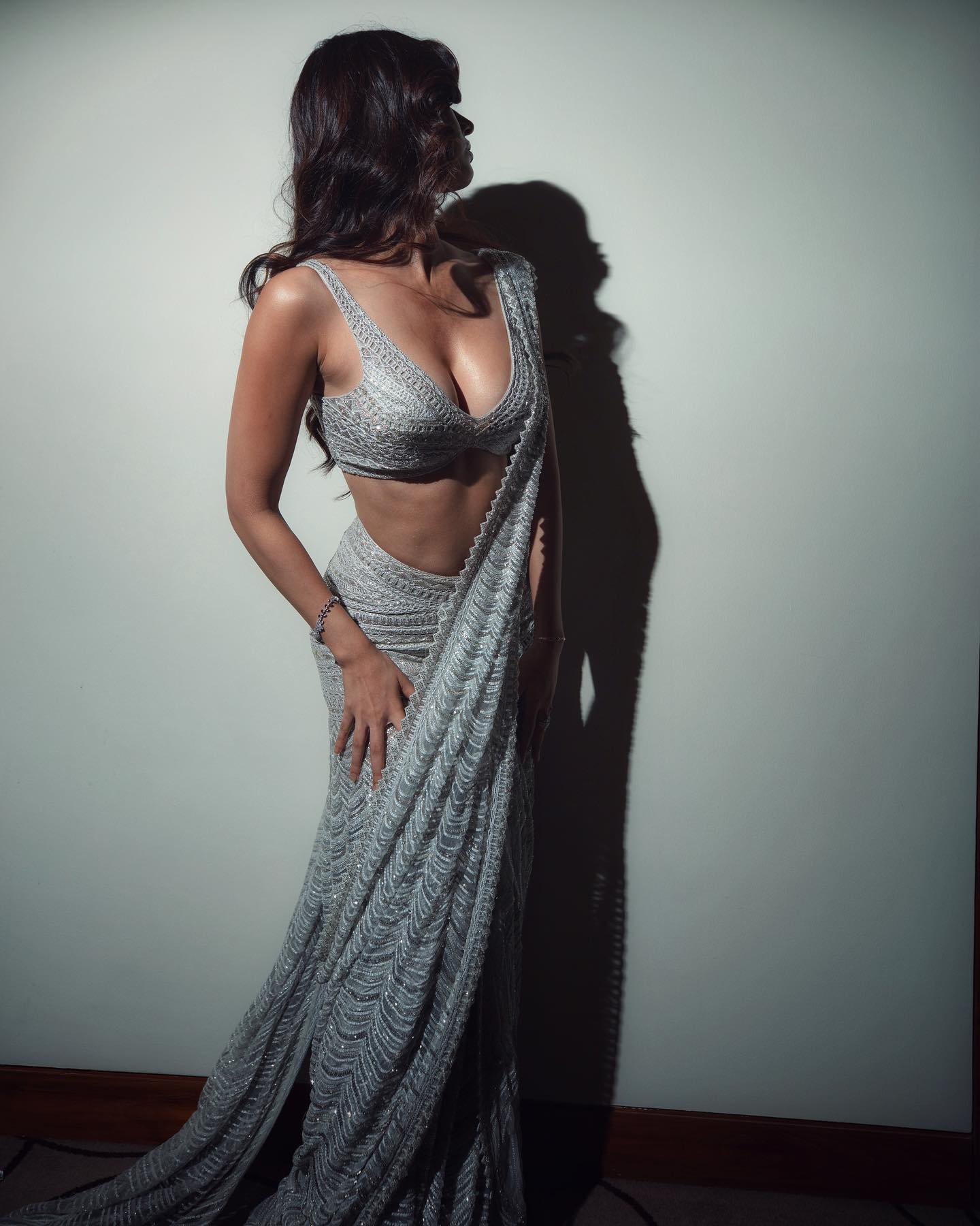 Disha Patani pairs the saree-lehenga with a deep-cut blouse that leaves little to the imagination. The actress poses with her face away from the camera, while just flaunting her toned figure