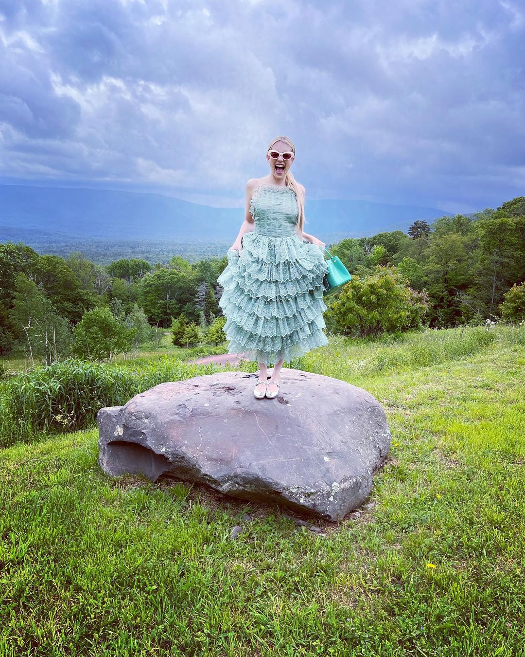 Emma Roberts strikes a silly pose on a rock.