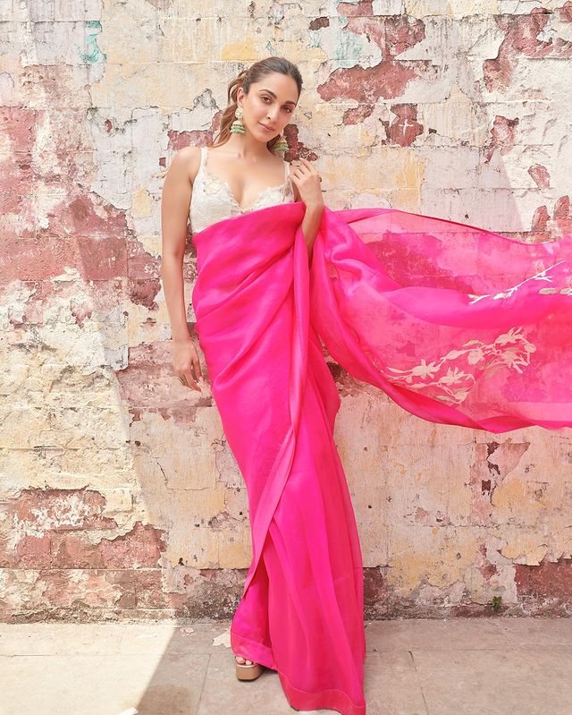 Kiara Advani embraces the Barbiecore trend by draping this beautiful pink saree. The actress wears it with a white sleeveless blouse. She opts for a contrasting green jhumka to accessorise. Kiara keeps her hair tied into a neat ponytail.