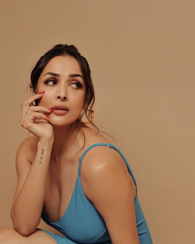 Malaika Arora keeps her hair tied into a messy updo that frames her face shape well. Smokey eye makeup, nude lips and red manicured nail complete her chic look. Malaika's wrist tattoo is also on display in this particular shot